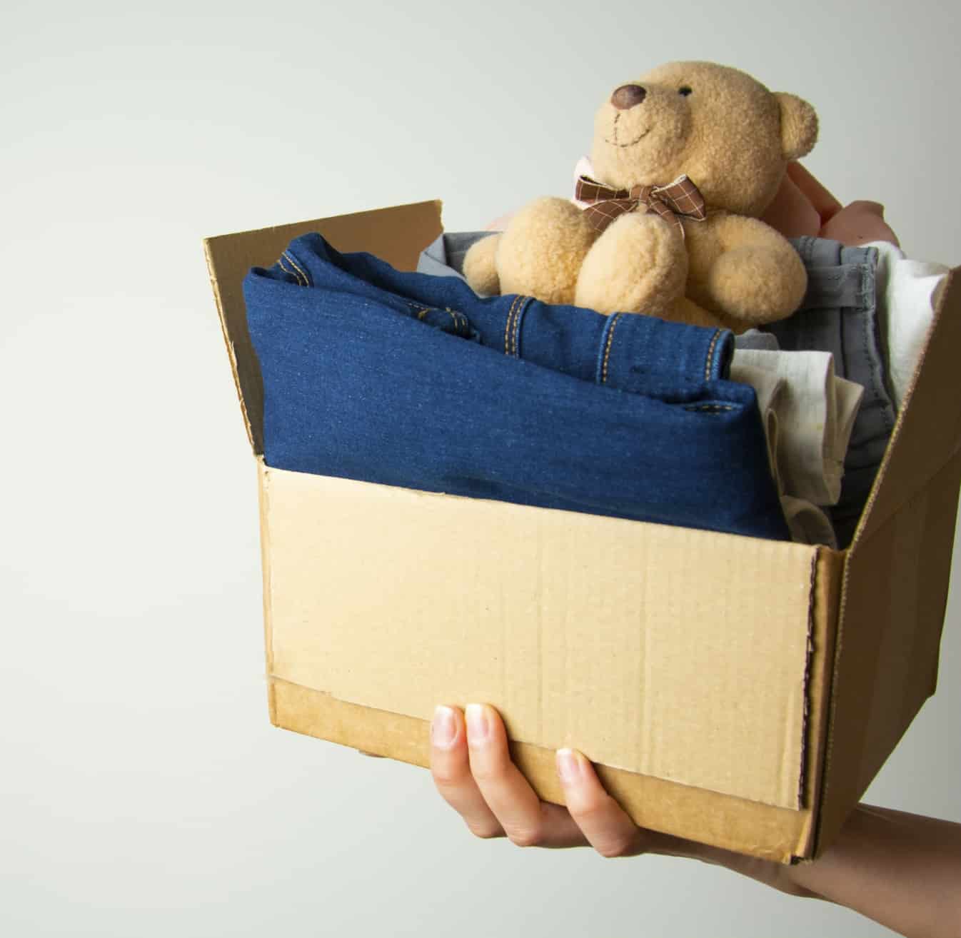 Donation concept. Hands holding donate box with clothes. Copy space.