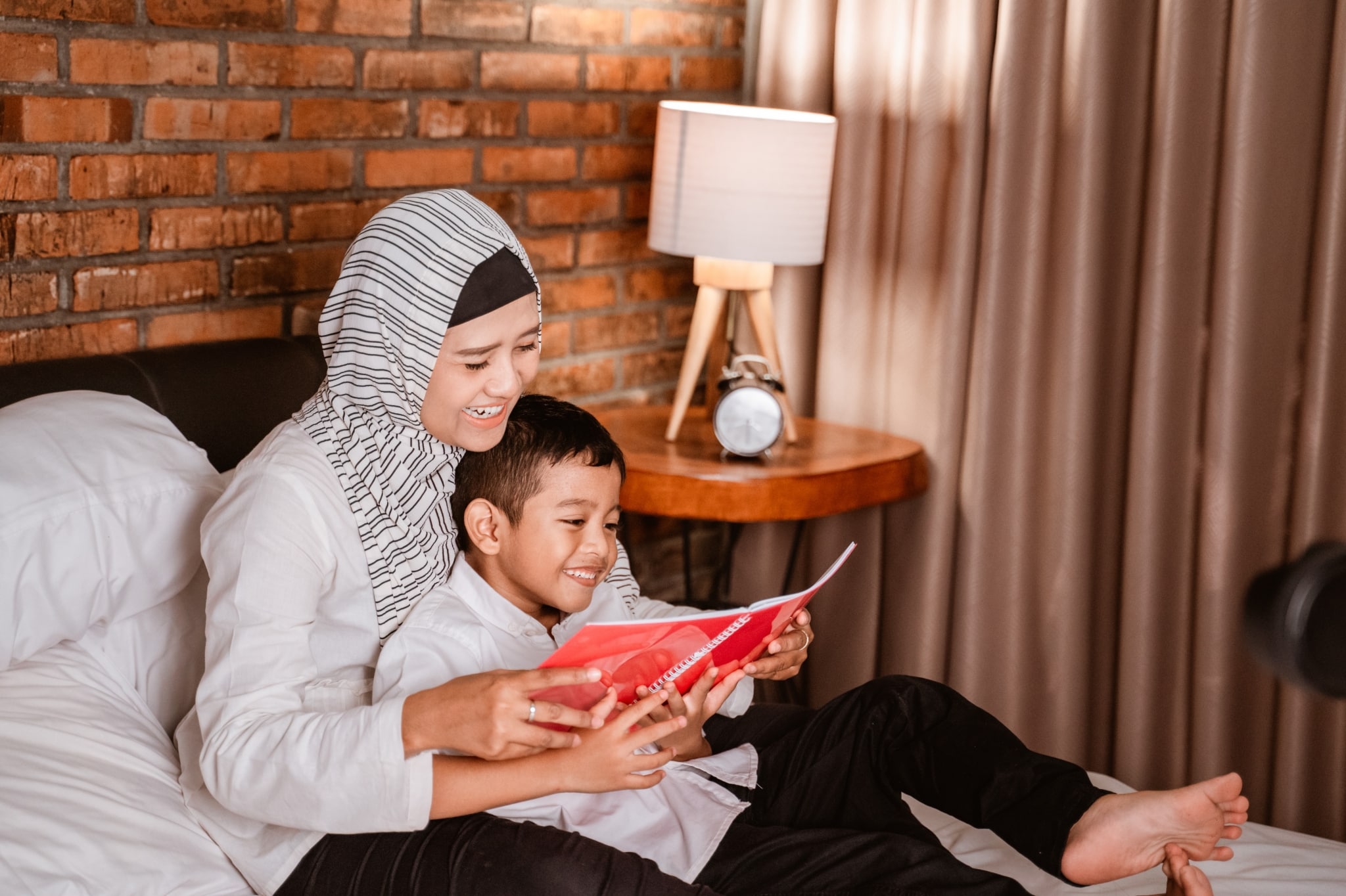 muslim mother reading a book with her son