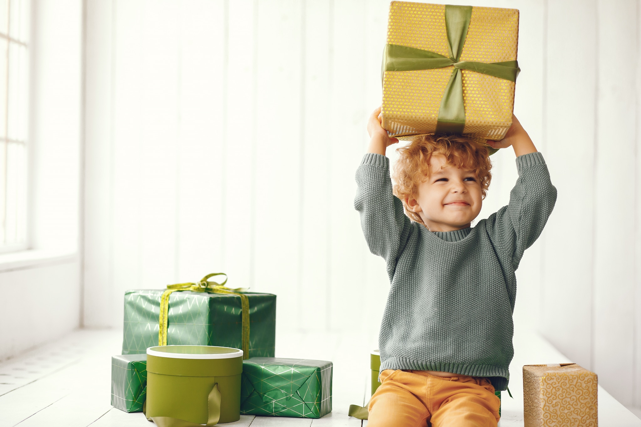 Little boy near christmas tree in a gray sweater